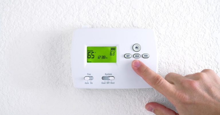hand switching on the emergency heat on the thermostat