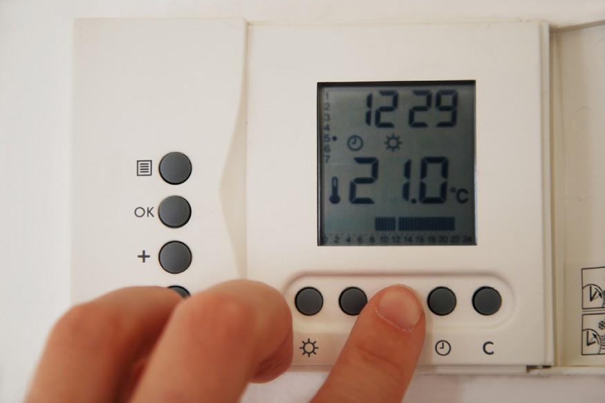 a hand setting the thermostat’s emergency heat