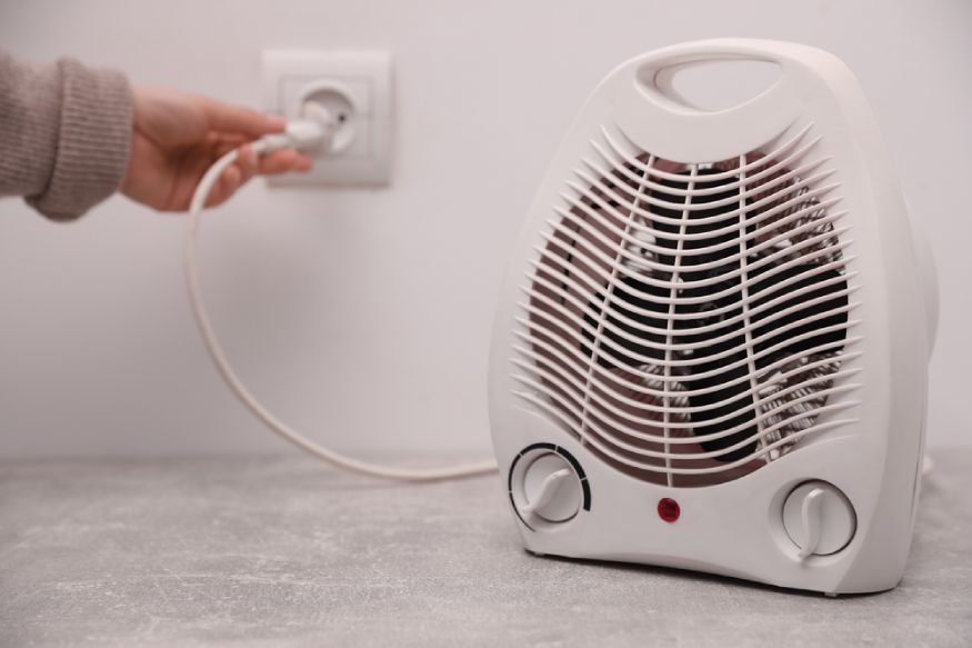 woman plugging in an electric heater with fan