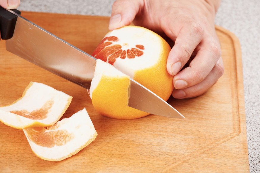 a person slicing a grapefruit