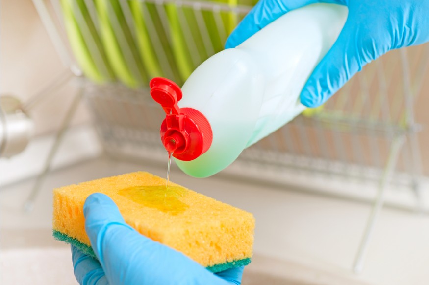 a person squeezing dish soap to a sponge