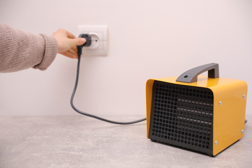 woman plugging in an electric fan heater