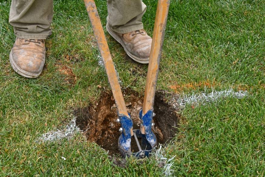 a person using a post hole digger