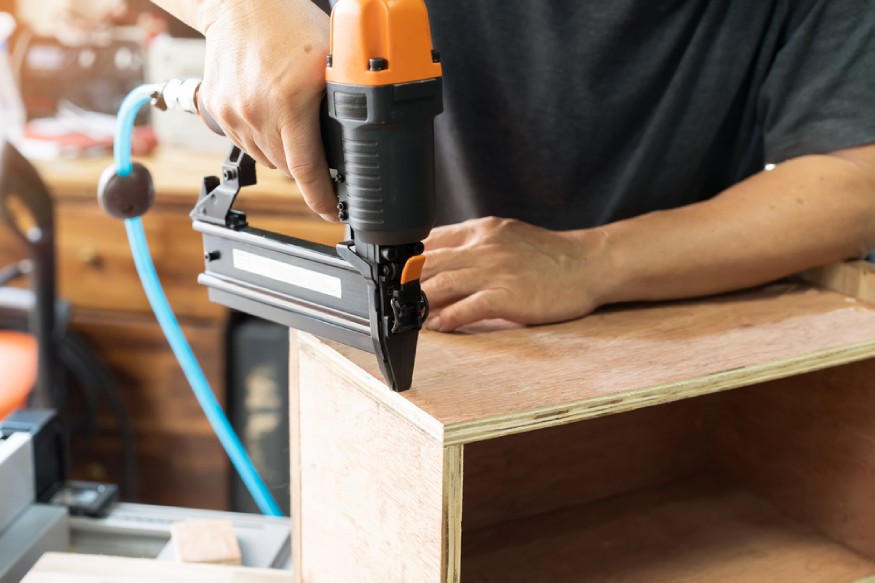 a carpenter using a pneumatic nail gun