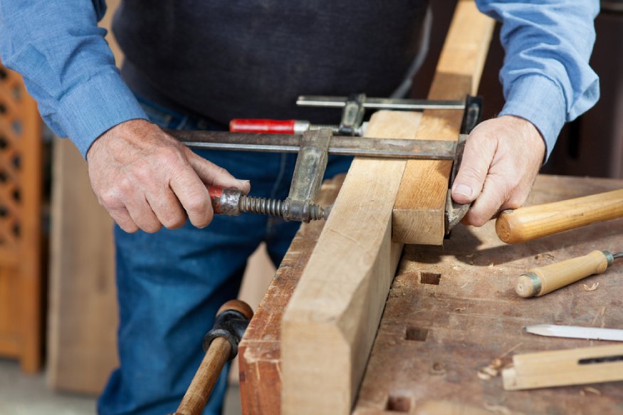 a carpenter using clamps to hold planks together
