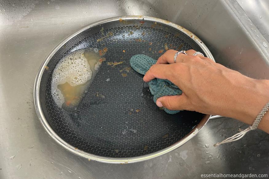 a woman using a rug to clean a HexClad pan