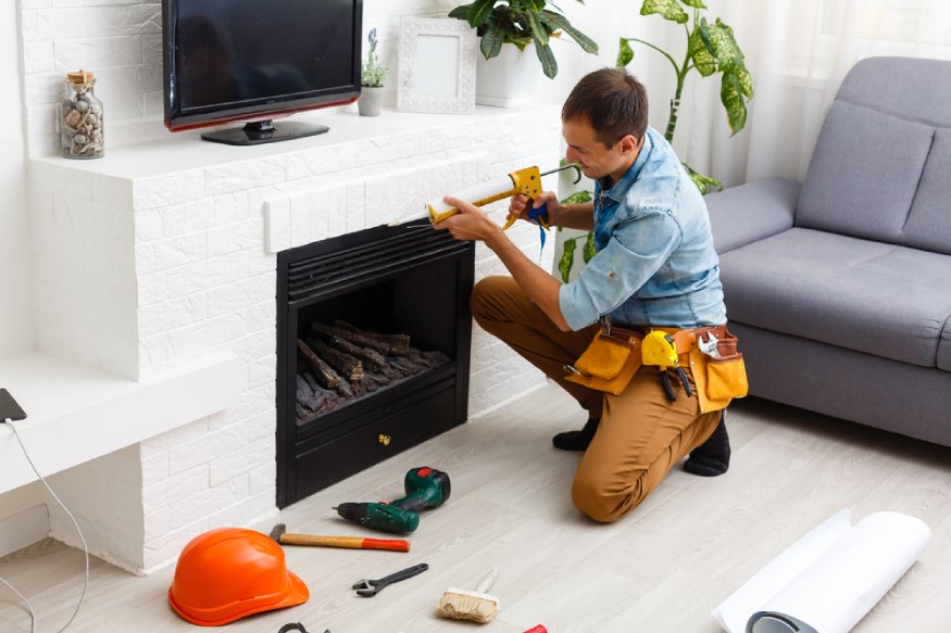 a handyman installing an electric fireplace insert