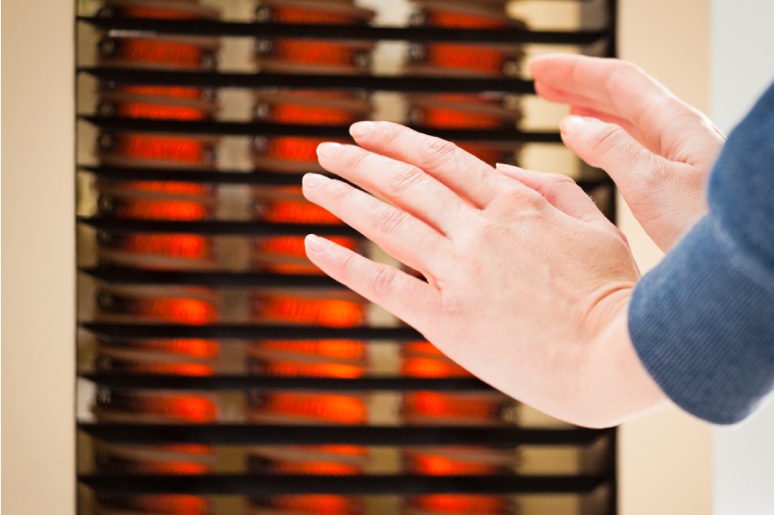 hands warming next to a heater with PTC heating element