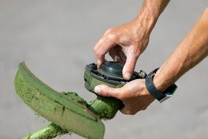 man opening the head of a Ryobi 18v string trimmer