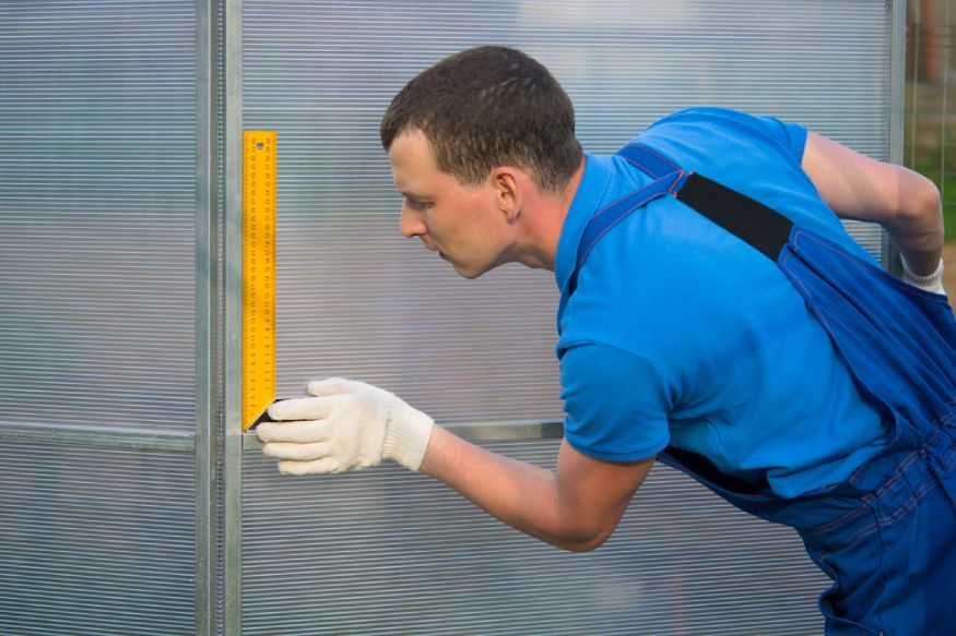 worker checking the walls of a greenhouse