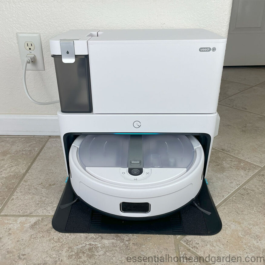 A yeedi cube robot vacuum sitting on top of a tile floor.