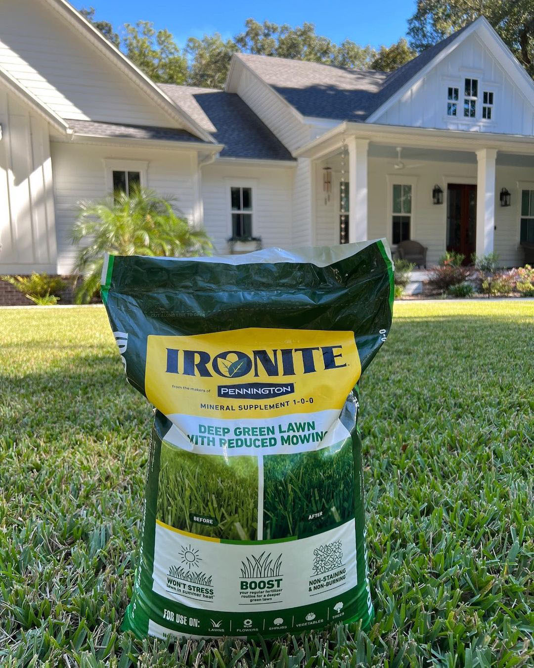 A bag of ironite green lawn in front of a house.
