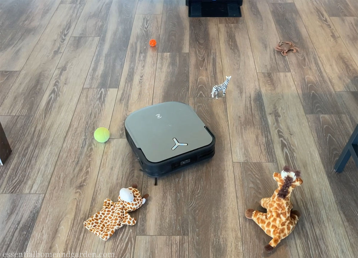 A robot vacuum cleaner with toys on the floor.