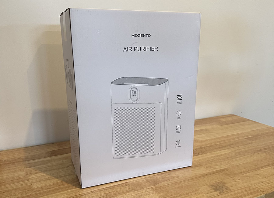 A boxed morento air purifier placed on a wooden shelf. the box features a line drawing of the product.