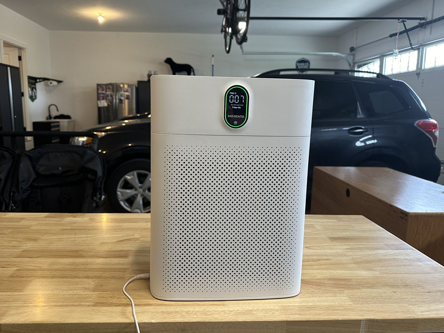 morento Air purifier on a wooden table in a garage, with a car visible in the background.