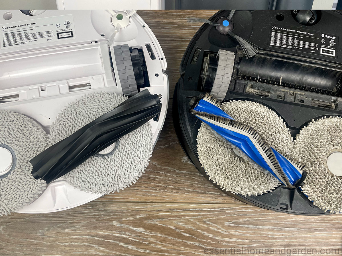 Two robotic vacuum cleaner bases on a wooden surface, each with rotating brushes and cleaning pads exposed for maintenance.