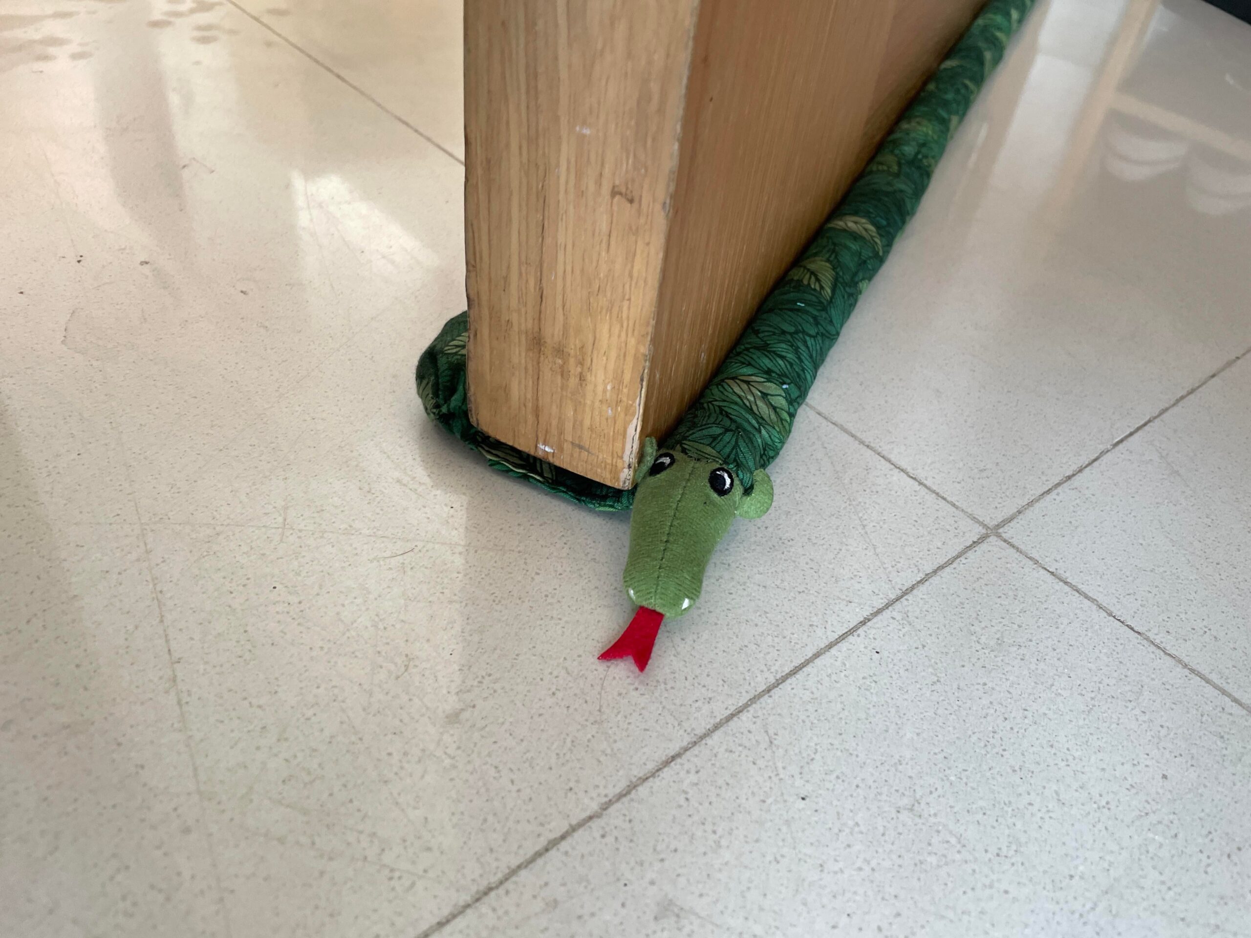Homemade knitted snake draft stopper lying along the bottom of a door