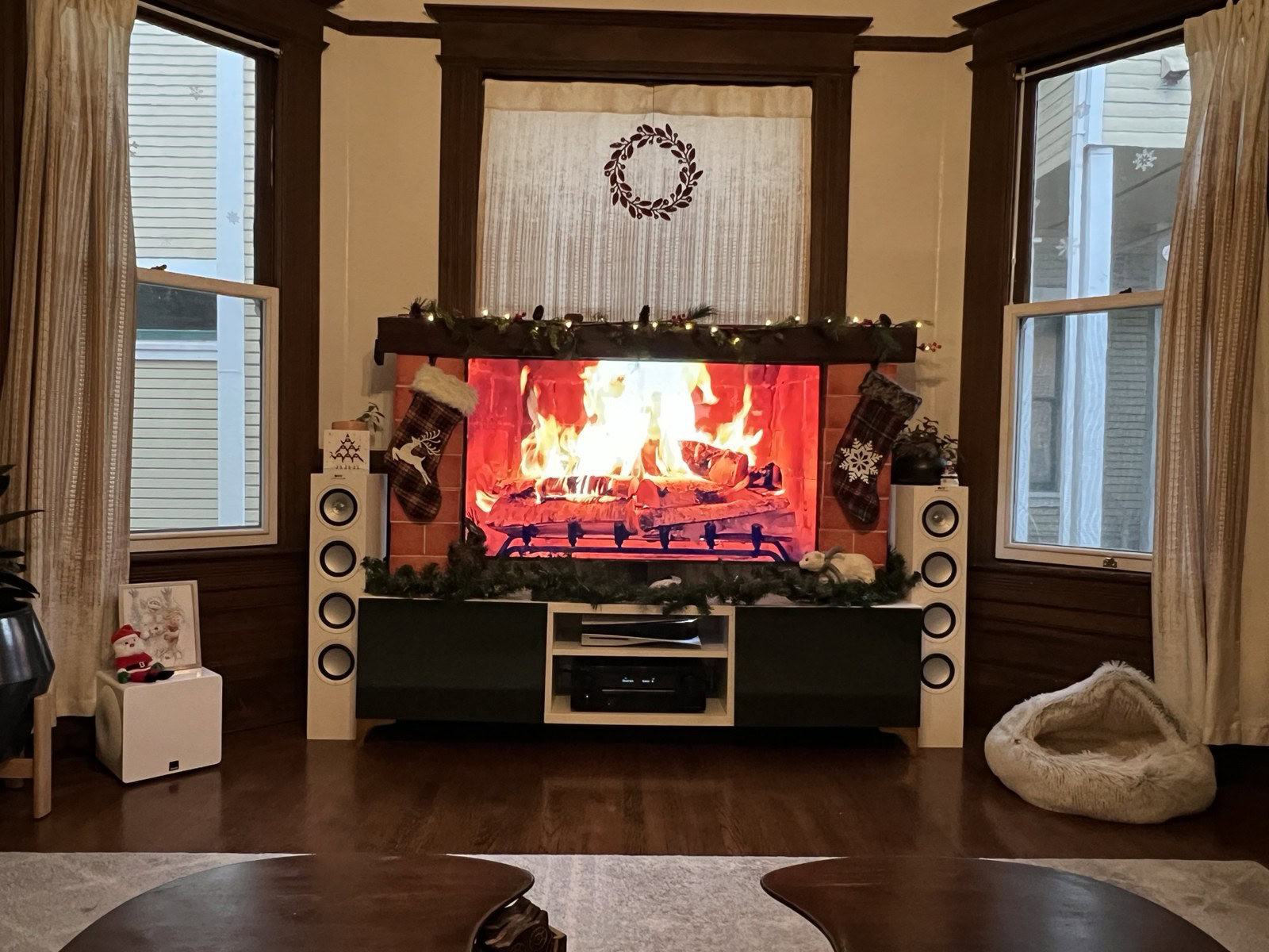 TV playing a fireplace video inside a mantel frame with a garland and stockings
