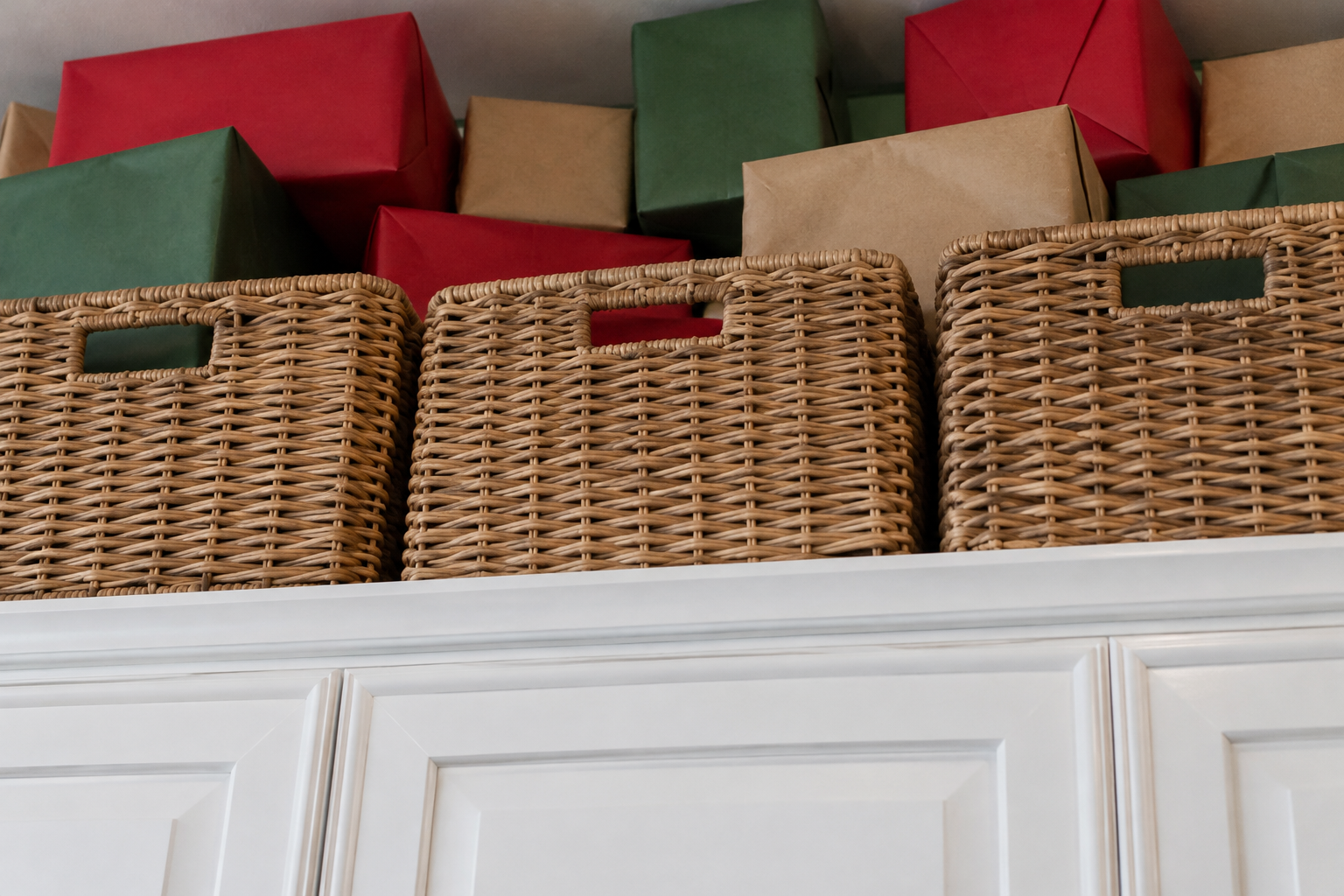 Wrapped presents on top of kitchen cabinets behind wicker baskets