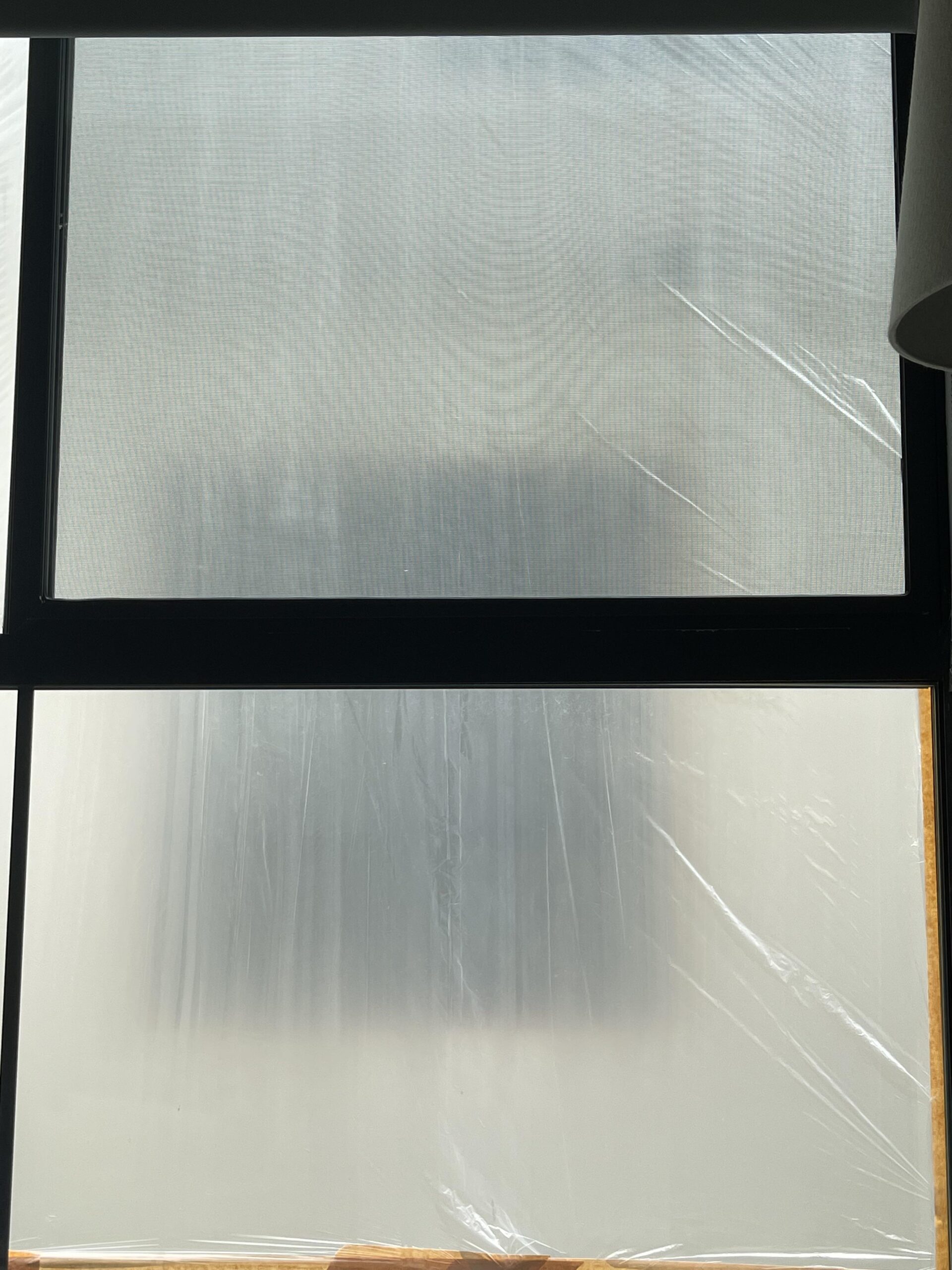 Clear plastic insulation film taped over a window, still cloudy before it is shrunk